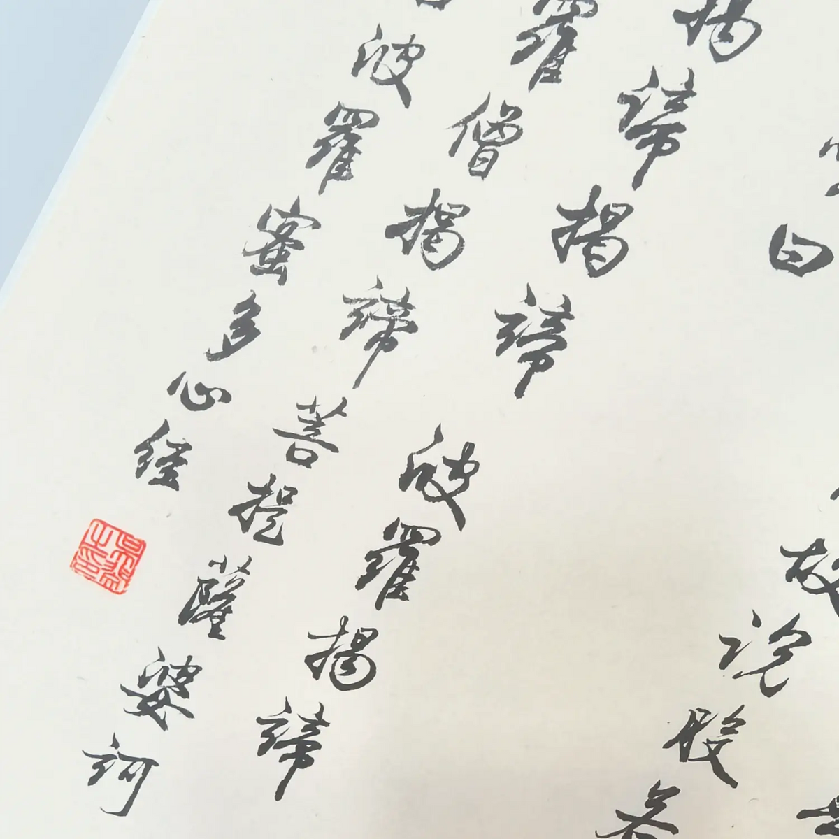 Close-up of handwritten Heart Sutra Chinese calligraphy in black ink on traditional Chinese calligraphy paper.