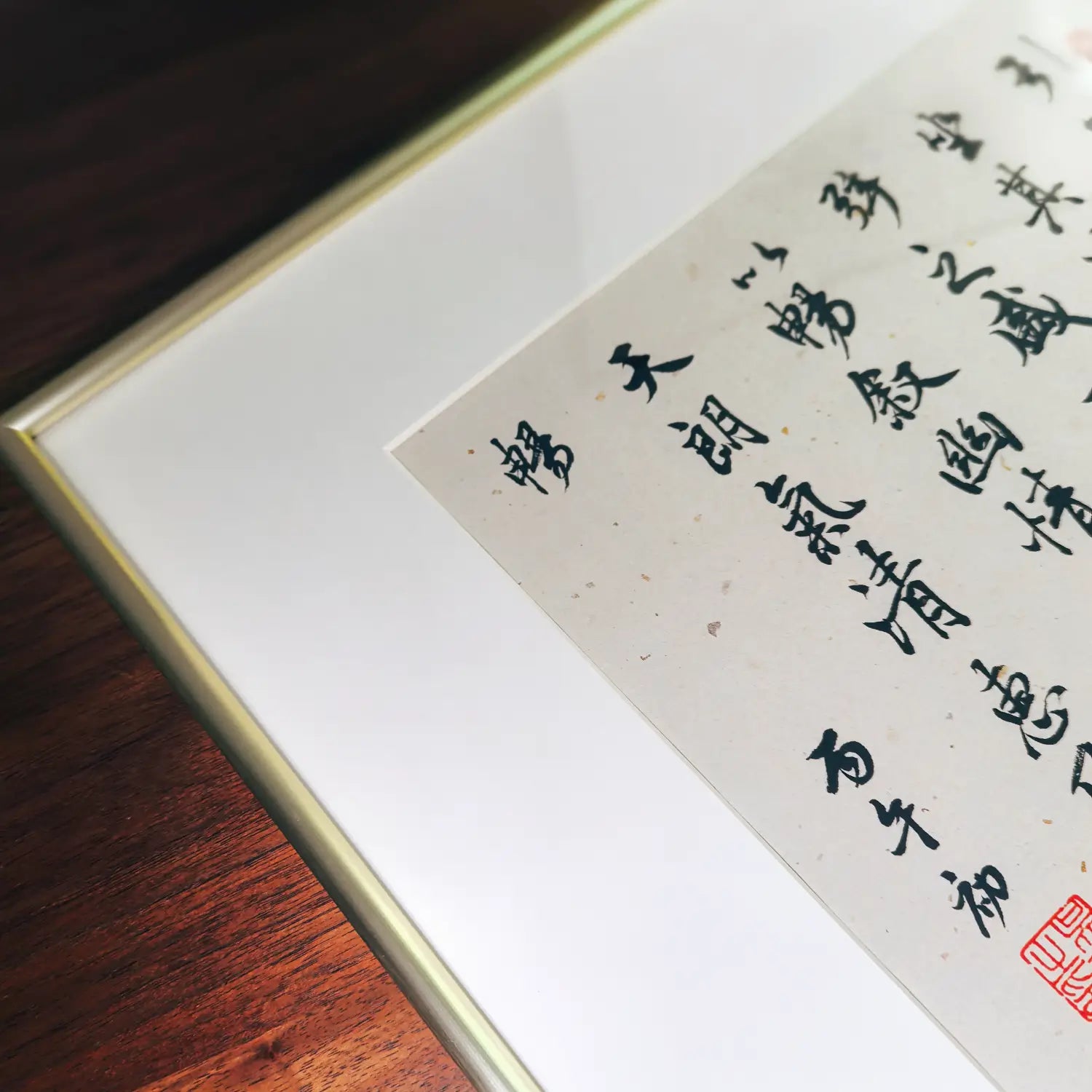 close shot of handwritten Chinese calligraphy wall art gold framed decor